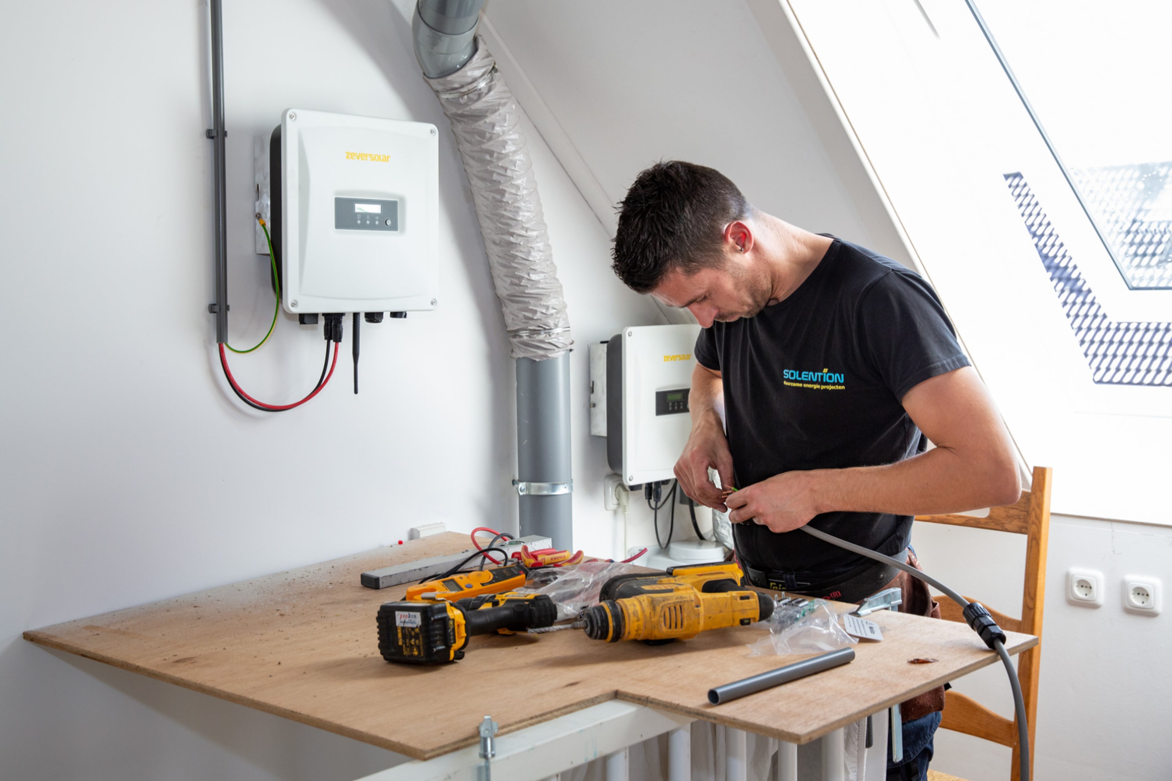 Man monteert omvormer. De omvormer vormt het hart van het systeem van zonnepanelen.