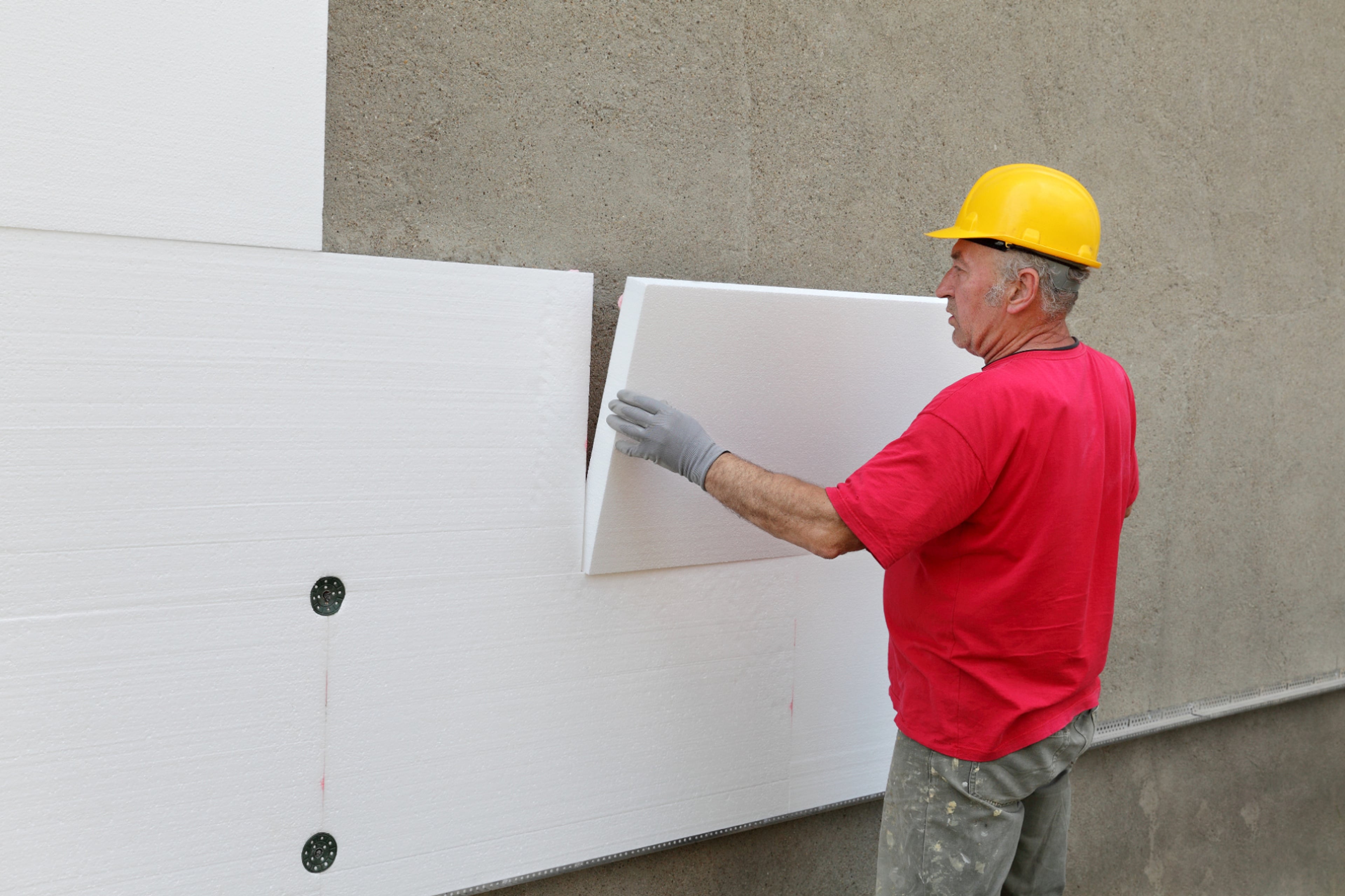Man plaatst gevelisolatie buitenwand. Buitenmuur isoleren aan de buitenkant.